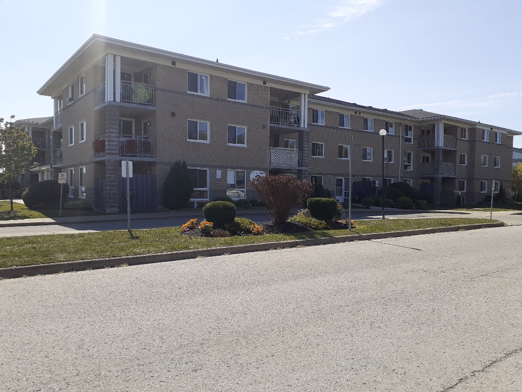 Front view of Arbour Village Co-op.  Three floors and balconies are in view as well as the sidewalk